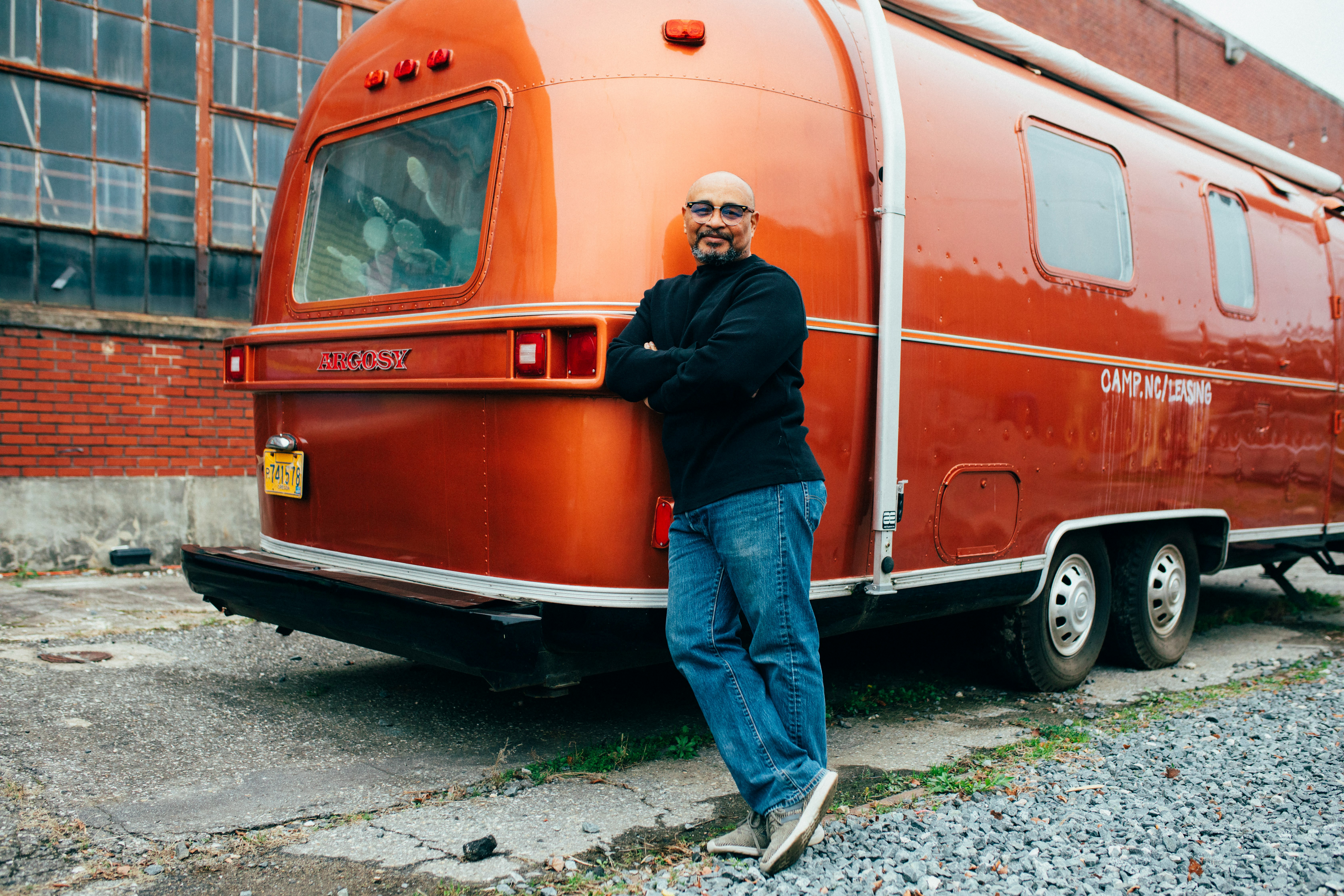 man leaning beside red vehicle